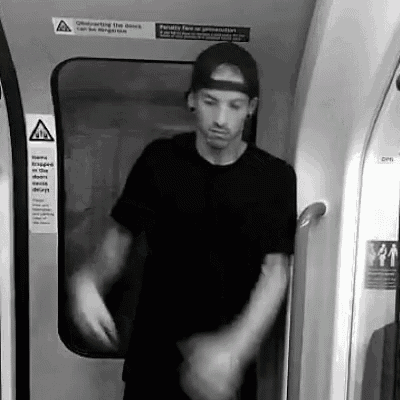 a man in a baseball cap is standing in the doorway of a subway car .
