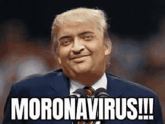 a man in a suit and tie is standing in front of a microphone and smiling while saying moron virus .