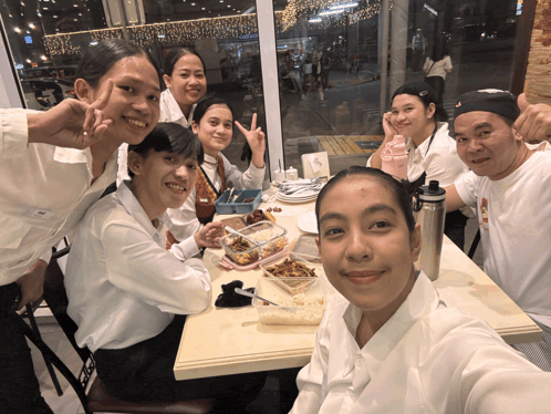a group of people sitting at a table with a man wearing a hat that says nike on it