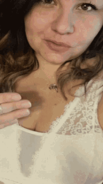 a woman is wearing a white bra and a necklace with a key on it