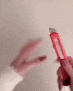 a person with long red nails is holding a red object between their fingers .