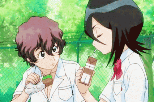 a boy and a girl are standing next to each other drinking from a box