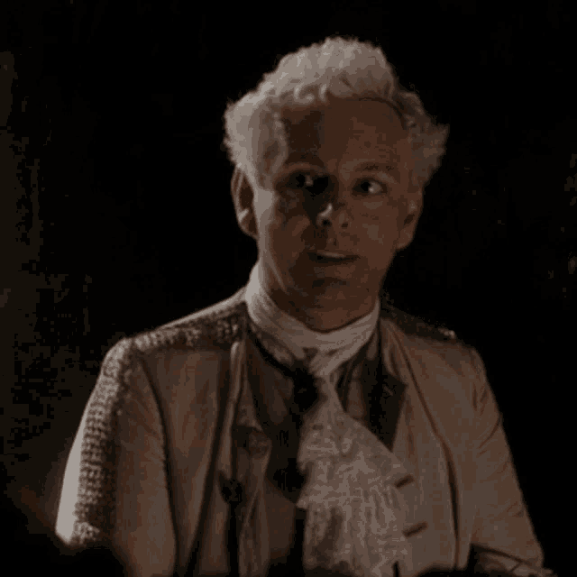 a man with white hair is wearing a suit and tie in a dark room