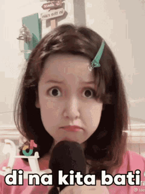 a young girl is holding a microphone and making a funny face .