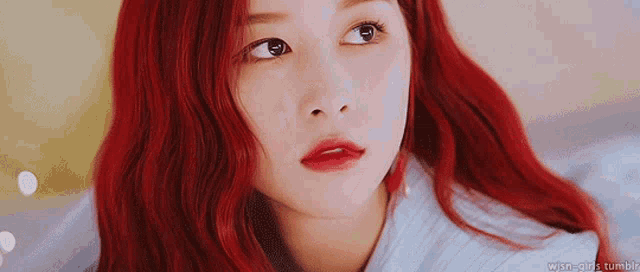a woman with red hair and red lips is looking at the camera .