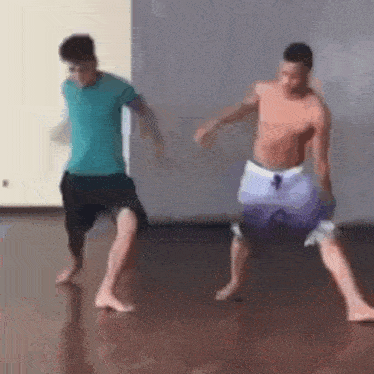 two men are dancing barefoot on a wooden floor in a gym .