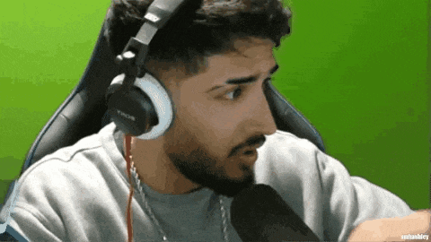 a man with a beard is wearing headphones and sitting in front of a microphone .