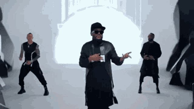 a man wearing sunglasses and a hat is standing in front of a group of men