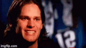 a man with long hair is smiling in front of a blue background with the number 12 on it .