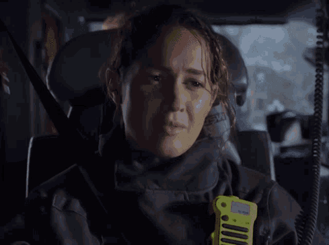 a woman wearing a black jacket and a yellow walkie talkie