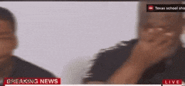 a man is covering his mouth in front of a breaking news screen .