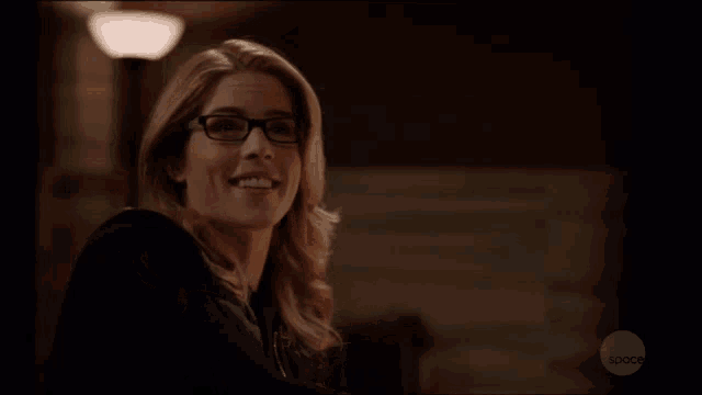 a woman wearing glasses is smiling and clapping in front of a screen that says space