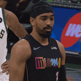 a man wearing a black miami jersey stands on a basketball court