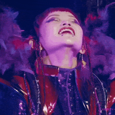 a close up of a woman 's face with purple feathers on her hair