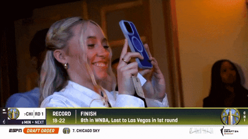 a woman is taking a picture of herself with a cell phone while watching a basketball game