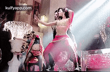 a woman in a red dress is dancing on a stage with other dancers .