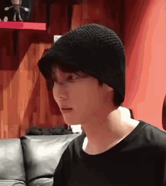 a man wearing a black hat is sitting on a couch in a room .