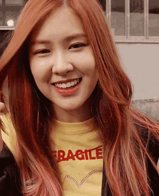a woman with red hair is wearing a yellow shirt that says fragile on it