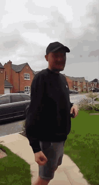 a man walking down a sidewalk in front of a row of houses