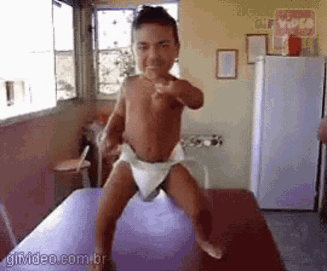 a baby in a diaper is pointing at the camera with gifvideo.com.br in the corner