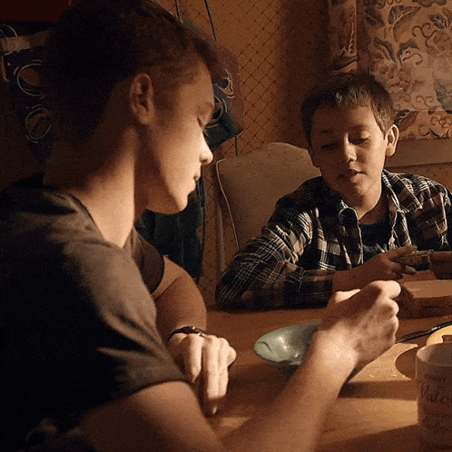 two young boys are sitting at a table with a cup that says mellow