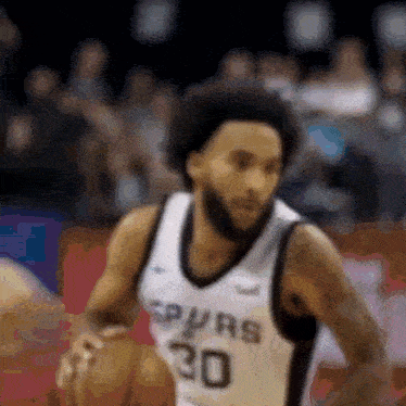 a basketball player wearing a spurs jersey is dribbling the ball