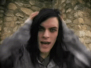 a man with long black hair is making a funny face in front of a stone wall