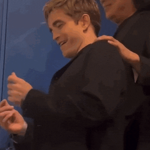 a man in a black suit is being hugged by another man