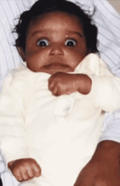 a baby making a funny face is being held by a person