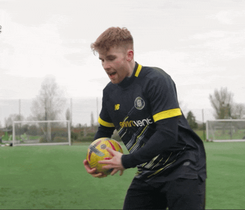 a man holding a soccer ball wearing a jersey that says skyventure
