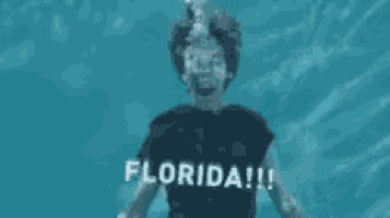 a man is swimming underwater in a pool with the words `` florida '' written on the water .