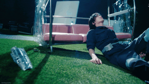 a man laying on the grass with a bottle of coca cola