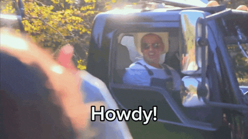 a man in a cowboy hat is sitting in the driver 's seat of a truck that says howdy