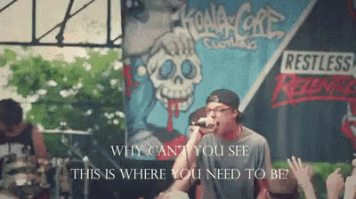 a man singing into a microphone in front of a sign that says restless rebels