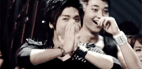 a group of young men are laughing and covering their faces in a crowd .
