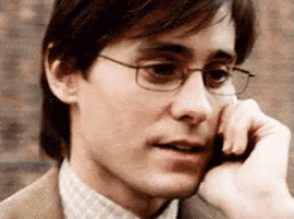 the man is wearing glasses and talking on a cell phone .