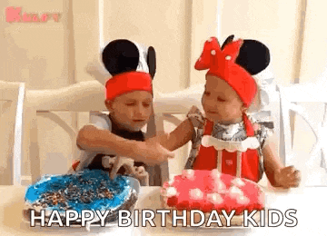 two little girls are sitting at a table with a birthday cake and candles .