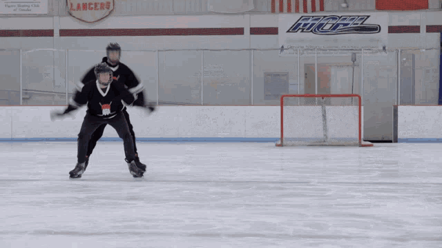 two hockey players on the ice in front of a lancers banner