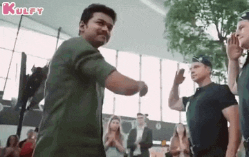 a man in a green shirt is dancing in front of a crowd of people in an airport .
