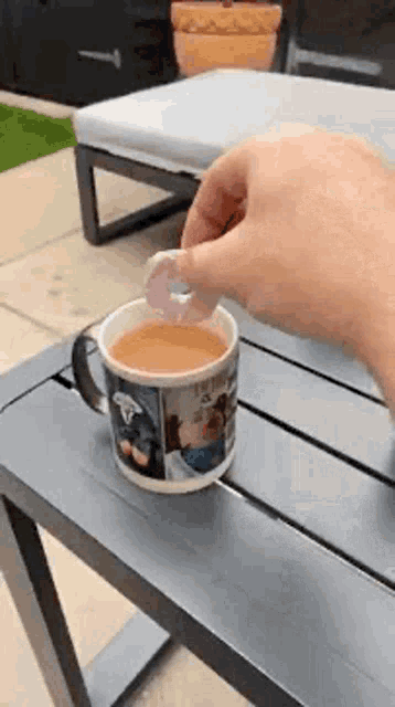 a person is putting a donut in a cup of tea .