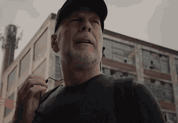 a man with a beard is wearing a hat and ear buds .