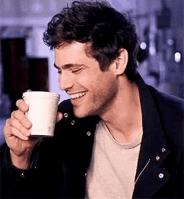 a man is smiling while drinking from a cup .