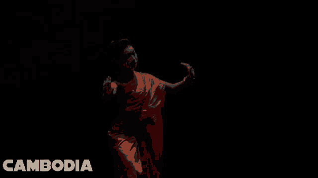 a woman in a green dress is dancing with the word cambodia behind her