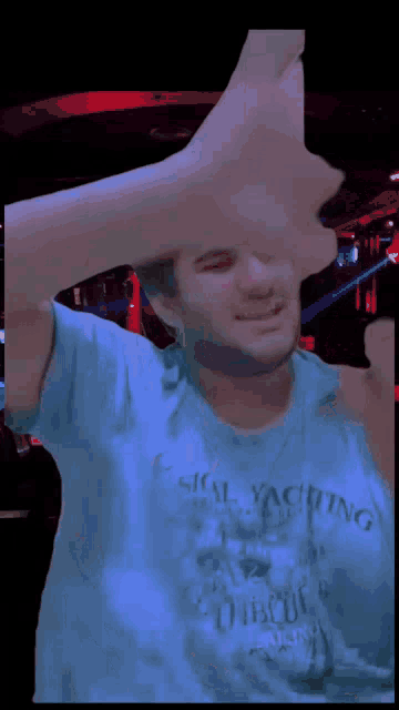 a man in a blue shirt is holding a stack of money in front of his face