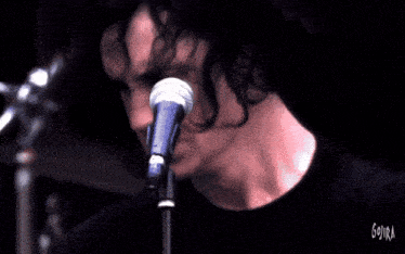 a man playing a guitar on a stage with a crowd in the background