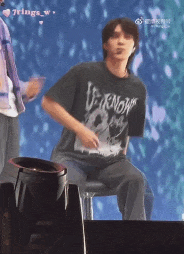 a man wearing a black venom shirt is sitting on a stage