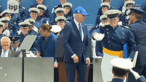 a man in a blue hat is standing in front of a group of military men
