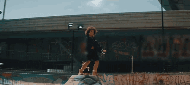 a person riding a skateboard in front of a wall with graffiti on it