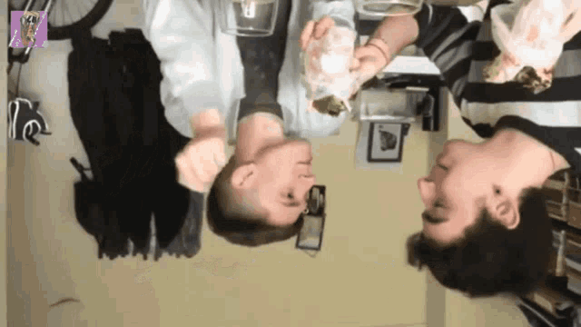 two men are standing upside down in a room and one is holding a glass