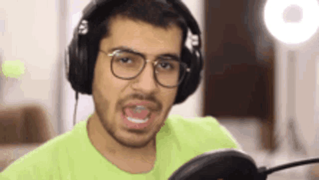 a man wearing headphones and a green shirt is making a funny face .